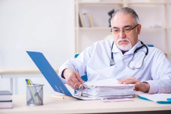 Oude mannelijke arts werkzaam in de kliniek — Stockfoto