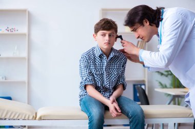 Male otolaryngologist examining boys ear clipart