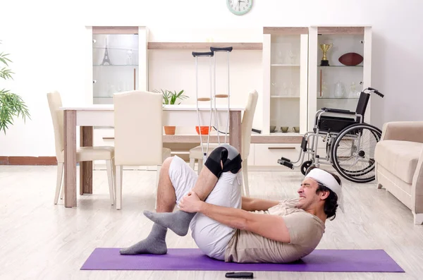 Jovem ferido fazendo exercícios em casa — Fotografia de Stock