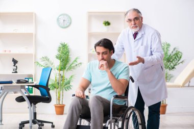 Tekerlekli sandalyedeki erkek hasta yaşlı doktoru ziyaret ediyor.
