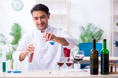 Erkek kimyager laboratuvarda şarap örneklerini inceliyor.