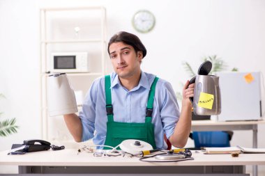 Hizmet merkezinde çaydanlığı tamir eden genç adam.