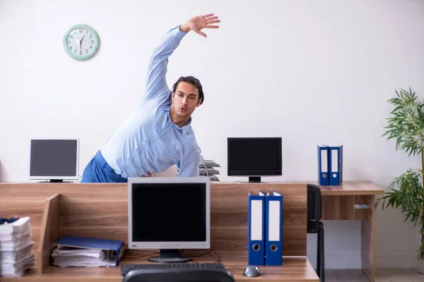 Joven hombre de negocios guapo haciendo ejercicios en el lugar de trabajo —  Fotos de Stock