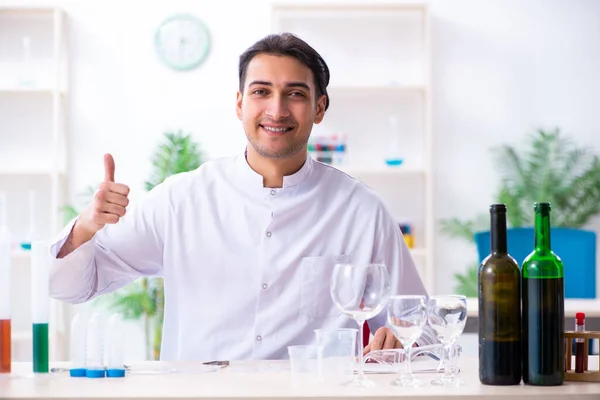 Químico masculino examinando amostras de vinho no laboratório — Fotografia de Stock