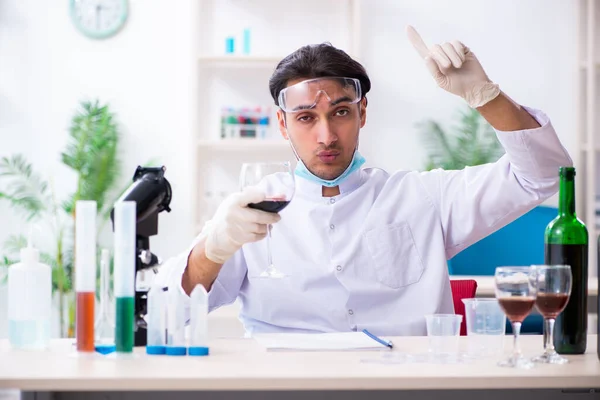 Chimico maschio che esamina campioni di vino in laboratorio — Foto Stock