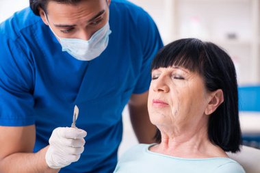 Yaşlı kadın estetik ameliyat için erkek doktoru ziyaret ediyor.