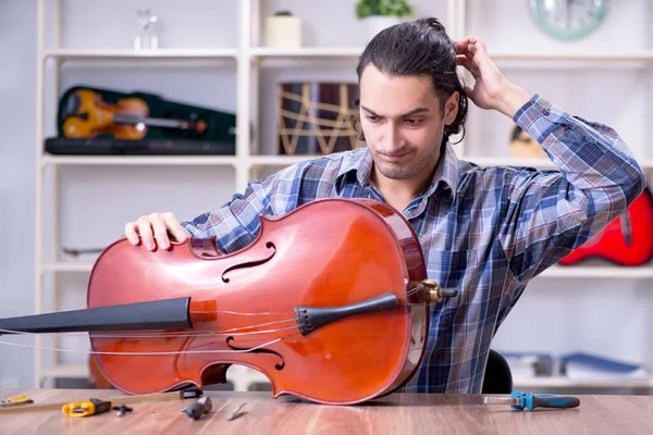 Giovane bel riparatore che ripara violoncello — Foto Stock