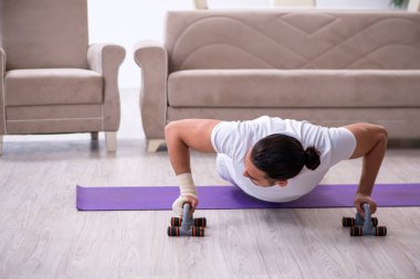 Evde egzersiz yapan eli yaralı bir adam var.