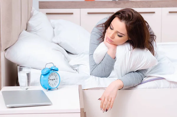 Jonge vrouw liggend op het bed in time management concept — Stockfoto
