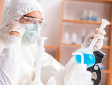 Laboratuvarda çalışan koruyucu elbise giyen genç bir biyokimyacı.