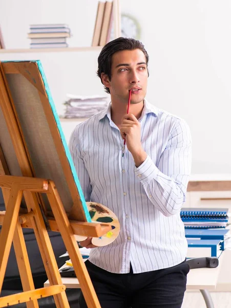 Jovem e bonito funcionário desfrutando de pintura no escritório — Fotografia de Stock