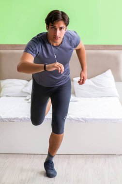 Genç yakışıklı adam otel odasında sabah egzersizi yapıyor.