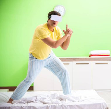 Yatak odasında sanal gözlüklü genç adam.
