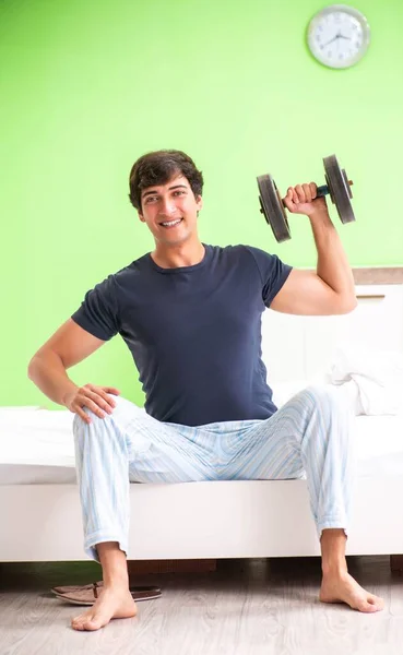 Молодой человек в пижаме делает утренние упражнения — стоковое фото