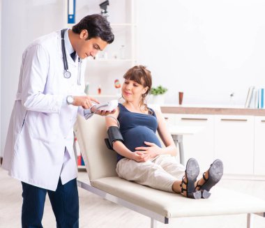 Genç doktor hamile kadınların kan basıncını ölçüyor.