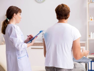 Erkek hasta genç bayan doktor kayropraktik uzmanını ziyaret ediyor.