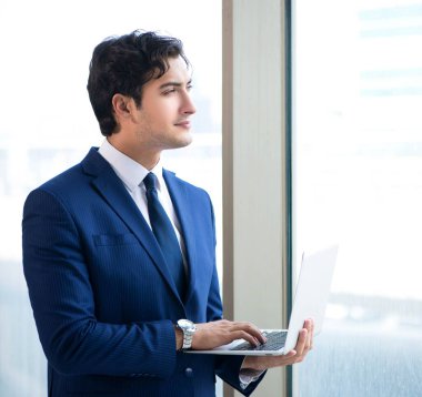 Genç yakışıklı işadamı pencerede duruyor.