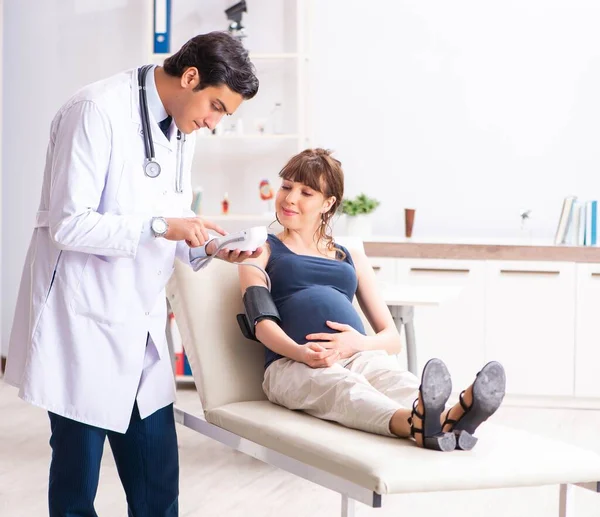 Junger Arzt überprüft Blutdruck von Schwangeren — Stockfoto