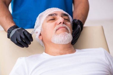 Yaşlı adam estetik ameliyat için erkek doktoru ziyaret ediyor.