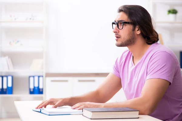 Jonge mannelijke student bereidt zich voor op examens in de klas — Stockfoto