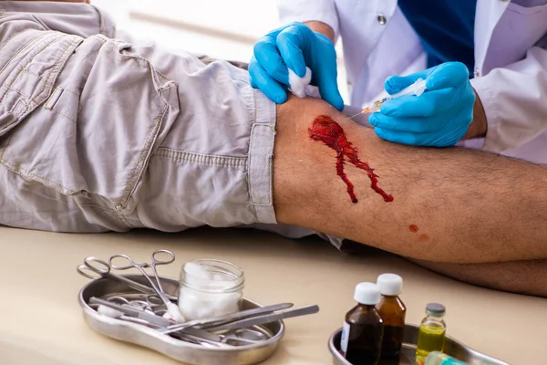 Homem ferido na perna visitando o velho médico no conceito de primeiros socorros — Fotografia de Stock