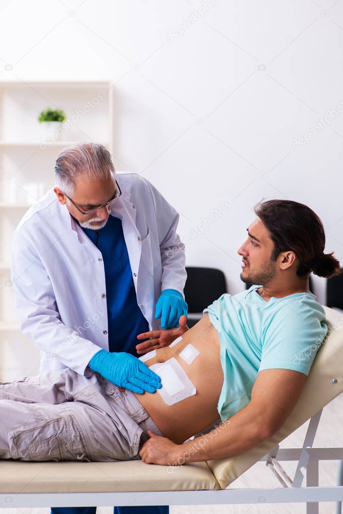 Injured young man visiting experienced male doctor