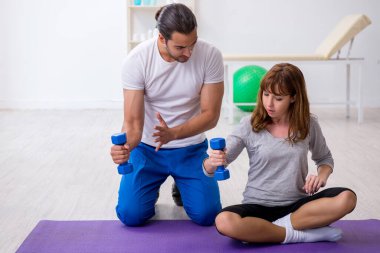 Kişisel koçla spor egzersizleri yapan genç bir kadın.