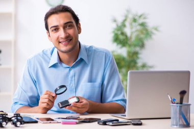 Cep telefonunu tamir eden genç bir teknisyen.