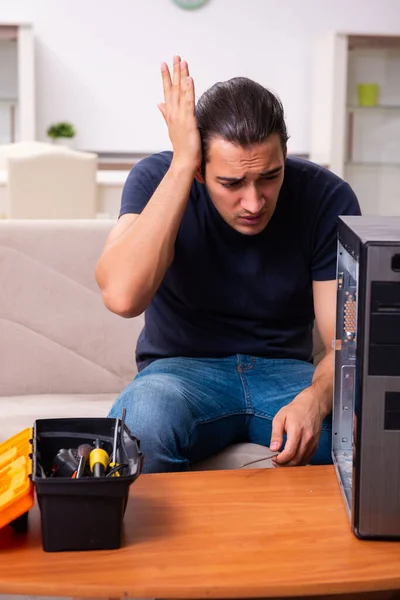 Młody człowiek naprawia komputer w domu — Zdjęcie stockowe