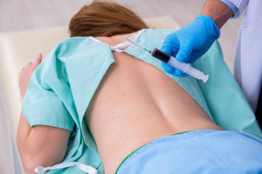 Genç sırtı yaralı kadın, erkek doktor masörünü ziyaret ediyor.