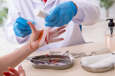 Yaralı kadın erkek doktoru ziyaret ediyor.
