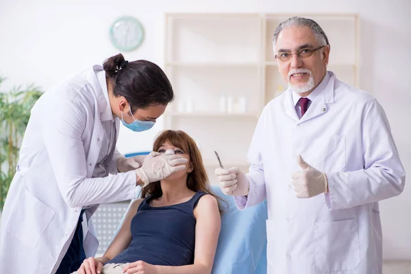 Deux médecins masculins et une jeune femme en chirurgie plastique concept — Photo