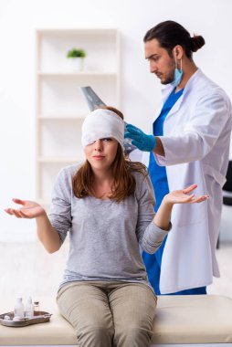 Genç baş yaralı kadın genç erkek doktoru ziyaret ediyor.