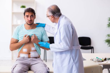 Yaralı genç adam deneyimli erkek doktoru ziyaret ediyor.