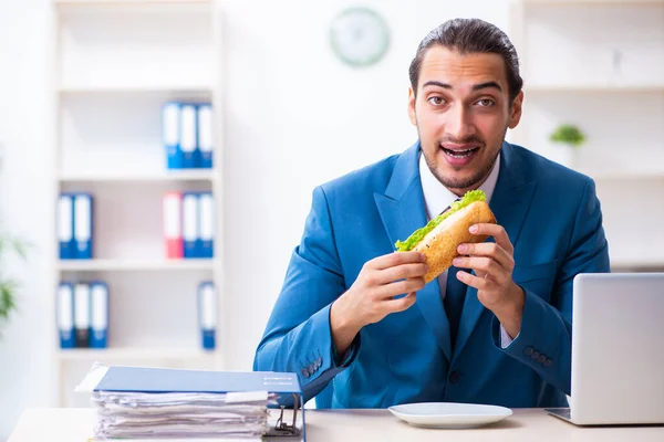 Jonge mannelijke werknemer ontbijten op de werkplek — Stockfoto