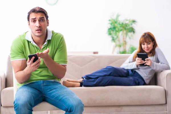Young couple in gadget dependency concept — Stock Photo, Image