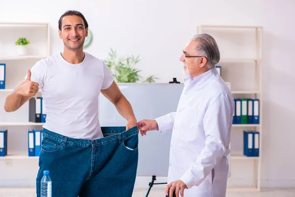 Doctor dietician and happy patient wearing large trousers — 图库照片