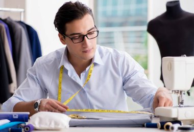 Genç terzi yeni elbiseler üzerinde çalışıyor.