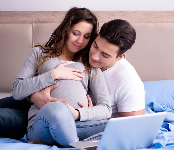 若いです家族とともに妊娠中の妻期待赤ちゃんでベッド — ストック写真