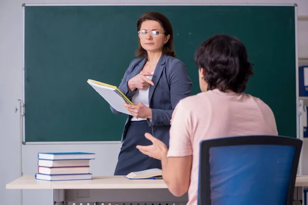 Oude vrouwelijke leraar en mannelijke student in de klas — Stockfoto