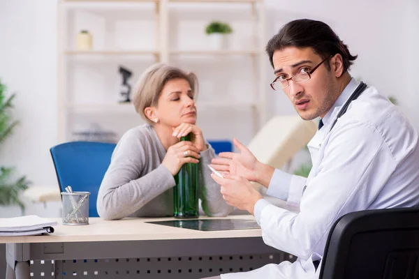 Vrouwelijke alcoholist op bezoek bij jonge mannelijke arts — Stockfoto