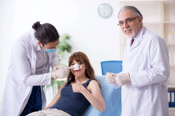 Deux médecins masculins et une jeune femme en chirurgie plastique concept — Photo