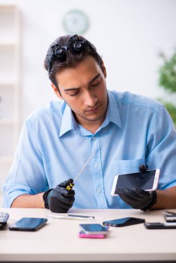 Cep telefonunu tamir eden genç bir teknisyen.