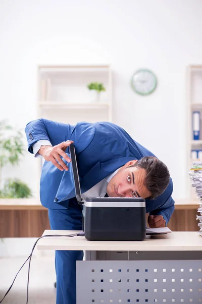 Young male employee making copies at copying machine — Stock Photo, Image