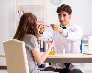 Genç bir kadın, erkek doktor göz doktorunu hastanede ziyaret ediyor.