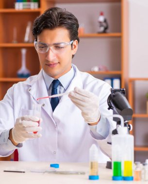 Genç yakışıklı biyokimyacı laboratuvarda çalışıyor.