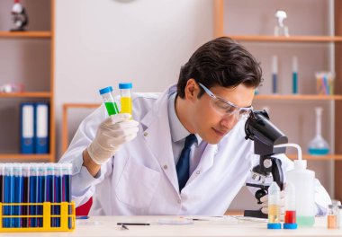 Genç yakışıklı biyokimyacı laboratuvarda çalışıyor.