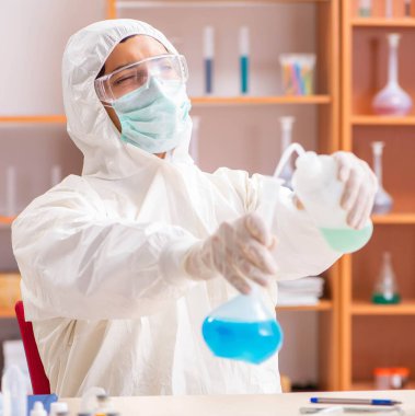 Laboratuvarda çalışan koruyucu elbise giyen genç bir biyokimyacı.