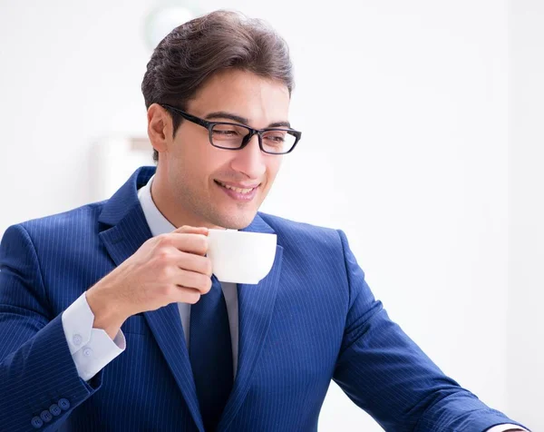 Junger schöner Geschäftsmann trinkt Kaffee im Büro — Stockfoto