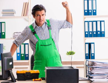 Ofiste bozuk bilgisayarı tamir eden genç bir mühendis.